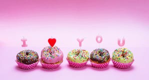 Las mini tortas con la congelación y colorido asperja en el fondo rosado, texto te amo imagenes de archivo Las mini tortas con la congelación y colorido asperja en el fondo rosado, texto te amo imagenes de archivo