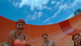 Las muchachas felices que van abajo de un waterslide en el agua parquean almacen de metraje de vídeo Las muchachas felices que van abajo de un waterslide en el agua parquean almacen de metraje de vídeo