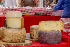 Las rondas apiladas del queso se exhiben en el mercado al aire libre de los granjeros mientras que tienda de la gente imagen de archivo libre de regalías Las rondas apiladas del queso se exhiben en el mercado al aire libre de los granjeros mientras que tienda de la gente imagen de archivo libre de regalías