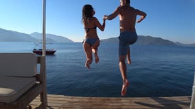 Las vacaciones de verano, los amigos felices con comienzo corriente saltan en el mar del embarcadero almacen de metraje de vídeo Las vacaciones de verano, los amigos felices con comienzo corriente saltan en el mar del embarcadero almacen de metraje de vídeo