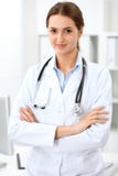 Latin - amerikanskt doktorskvinnaanseende med armar som korsas och les på sjukhuset Läkare som är klar att undersöka patienten royaltyfri fotografi Latin - amerikanskt doktorskvinnaanseende med armar som korsas och les på sjukhuset Läkare som är klar att undersöka patienten royaltyfri fotografi