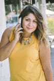Hispanic Young Girl Holds a Cell Phone to Her Ear While Smiling and Happy Millennial Fashion Casual stock photo Hispanic Young Girl Holds a Cell Phone to Her Ear While Smiling and Happy Millennial Fashion Casual stock photo