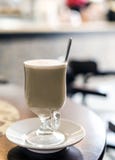 Latte da xícara de café com colher para dentro no café fotografia de stock Latte da xícara de café com colher para dentro no café fotografia de stock