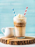 Lattemacchiato met slagroom in lang glas en waterkruik op ronde houten raad over blauwe geschilderde muurachtergrond royalty-vrije stock foto's Lattemacchiato met slagroom in lang glas en waterkruik op ronde houten raad over blauwe geschilderde muurachtergrond royalty-vrije stock foto's