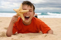 Laughing boy with starfish on the beach