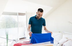 Smiling man with laundry and drying rack at home Stock Image Smiling man with laundry and drying rack at home Stock Image