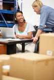 Lavoratore in cuffia avricolare del magazzino e computer portatile d'uso usando immagini stock Lavoratore in cuffia avricolare del magazzino e computer portatile d'uso usando immagini stock