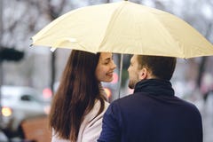 Le belle coppie, il tipo e la sua amica vestiti in abbigliamento casual stanno sotto l'ombrello ed esaminarse sopra fotografie stock Le belle coppie, il tipo e la sua amica vestiti in abbigliamento casual stanno sotto l'ombrello ed esaminarse sopra fotografie stock