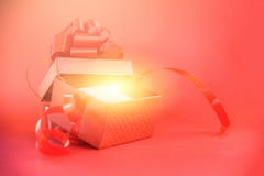 Le boîte-cadeau ouvert rayonne la lumière sur le fond rouge/boîte actuelle rouge avec l'arc rouge de ruban pendant la bonne année images stock Le boîte-cadeau ouvert rayonne la lumière sur le fond rouge/boîte actuelle rouge avec l'arc rouge de ruban pendant la bonne année images stock