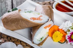 Le burrito de sushi roule avec le fromage de saumon et fondu, l'avocat et le concombre sur le plat photos stock Le burrito de sushi roule avec le fromage de saumon et fondu, l'avocat et le concombre sur le plat photos stock
