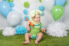 Le bébé garçon dans le costume de lapin de Pâques de vacances avec de grandes oreilles, habillées en vert vêtx l'onesie, se repos Image stock Le bébé garçon dans le costume de lapin de Pâques de vacances avec de grandes oreilles, habillées en vert vêtx l'onesie, se repos Image stock