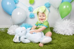 Le bébé garçon dans le costume de lapin de Pâques de vacances avec de grandes oreilles, habillées en vert vêtx l'onesie, se repos Images libres de droits Le bébé garçon dans le costume de lapin de Pâques de vacances avec de grandes oreilles, habillées en vert vêtx l'onesie, se repos Images libres de droits