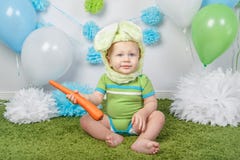 Le bébé garçon dans le costume de lapin de Pâques de vacances avec de grandes oreilles, habillées en vert vêtx l'onesie, se repos Photos stock Le bébé garçon dans le costume de lapin de Pâques de vacances avec de grandes oreilles, habillées en vert vêtx l'onesie, se repos Photos stock