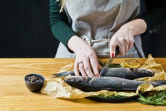 Le chef prépare le bar de mer sur une table en bois Fond noir, vue de côté, l'espace pour le texte images stock Le chef prépare le bar de mer sur une table en bois Fond noir, vue de côté, l'espace pour le texte images stock