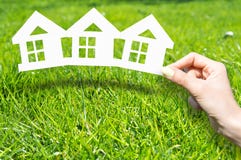 Le concept à la maison d'assurance avec la main tenant la maison a formé des documents imprimés sur l'herbe verte image stock Le concept à la maison d'assurance avec la main tenant la maison a formé des documents imprimés sur l'herbe verte image stock