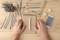 Le concepteur dessine un croquis dans un carnet sur une table en bois papeterie Vue de ci-avant photographie stock libre de droits Le concepteur dessine un croquis dans un carnet sur une table en bois papeterie Vue de ci-avant photographie stock libre de droits