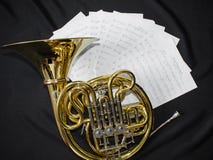 Le cor d'harmonie d'instrument de musique se trouve sur un fond noir avec des notes photo libre de droits Le cor d'harmonie d'instrument de musique se trouve sur un fond noir avec des notes photo libre de droits