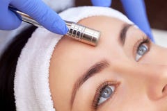 Le cosmetologist fait la procédure Microdermabrasion de la peau faciale d'un beau, jeune femme dans un salon de beauté Le cosme photo libre de droits Le cosmetologist fait la procédure Microdermabrasion de la peau faciale d'un beau, jeune femme dans un salon de beauté Le cosme photo libre de droits