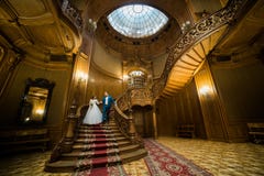 Le couple gai de nouveaux mariés groing en bas des escaliers antiques Vue horizontale photos libres de droits Le couple gai de nouveaux mariés groing en bas des escaliers antiques Vue horizontale photos libres de droits