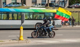 Le couple monte une moto avec le drapeau lithuanien image libre de droits Le couple monte une moto avec le drapeau lithuanien image libre de droits