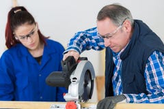 Le cours de menuiserie d'And Teacher In d'?tudiant utilisant circulaire a vu photographie stock libre de droits Le cours de menuiserie d'And Teacher In d'?tudiant utilisant circulaire a vu photographie stock libre de droits