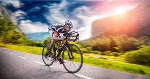 Le cycliste monte sur la bicyclette, effet de vitesse, vue de côté image stock Le cycliste monte sur la bicyclette, effet de vitesse, vue de côté image stock