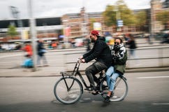 Le cycliste porte la jeune femme sur la tache floue de mouvement de bicyclette, Amsterdam images libres de droits Le cycliste porte la jeune femme sur la tache floue de mouvement de bicyclette, Amsterdam images libres de droits