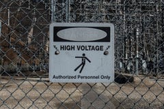 Le danger à haute tension fané se connectent Chainlink Photos stock Le danger à haute tension fané se connectent Chainlink Photos stock