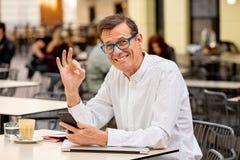 Le den attraktiva stilfulla mogna mannen som använder den smarta telefonen som arbetar online-sammanträde utanför coffee shop royaltyfri fotografi Le den attraktiva stilfulla mogna mannen som använder den smarta telefonen som arbetar online-sammanträde utanför coffee shop royaltyfri fotografi