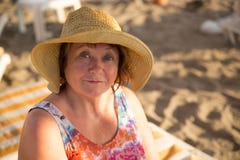 Le den bärande hatten för hög kvinna på stranden på sunbed Arkivfoto Le den bärande hatten för hög kvinna på stranden på sunbed Arkivfoto