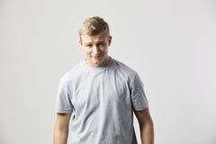 Le den iklädda blonda grabben står en vit t-skjorta på den vita bakgrunden i studion royaltyfria foton Le den iklädda blonda grabben står en vit t-skjorta på den vita bakgrunden i studion royaltyfria foton