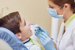 Le dentiste traite les dents d'un enfant à un garçon dans un bureau dentaire image libre de droits Le dentiste traite les dents d'un enfant à un garçon dans un bureau dentaire image libre de droits