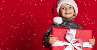Le det roliga barnet i gåva för jul för röd hatt för jultomten hållande i hand Julfilial och klockor royaltyfria foton Le det roliga barnet i gåva för jul för röd hatt för jultomten hållande i hand Julfilial och klockor royaltyfria foton