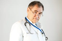 Le docteur examine la distance, il est habillé dans une robe longue blanche et un stéthoscope traîne son cou photo stock Le docteur examine la distance, il est habillé dans une robe longue blanche et un stéthoscope traîne son cou photo stock