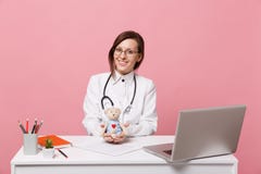 Le docteur féminin s'asseyent au travail de bureau sur l'ordinateur avec le jouet médical de prise de document dans l'hôpital d'i images stock Le docteur féminin s'asseyent au travail de bureau sur l'ordinateur avec le jouet médical de prise de document dans l'hôpital d'i images stock