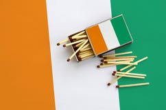 Le drapeau de la Côte d'Ivoire est montré sur une boîte d'allumettes ouverte, de laquelle plusieurs matchs tombent et des mensong photos libres de droits Le drapeau de la Côte d'Ivoire est montré sur une boîte d'allumettes ouverte, de laquelle plusieurs matchs tombent et des mensong photos libres de droits