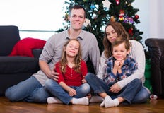 Le familjemedlemmar som förbereder sig för foto med julgranen royaltyfri bild Le familjemedlemmar som förbereder sig för foto med julgranen royaltyfri bild