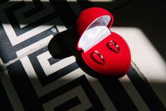 Le fedi nuziali si trovano in una cassa in forma di cuore rossa fotografie stock Le fedi nuziali si trovano in una cassa in forma di cuore rossa fotografie stock