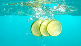 Le fette del limone stanno cadendo in acqua blu con il ripiano del tavolo subacqueo del colpo delle bolle al rallentatore video d archivio Le fette del limone stanno cadendo in acqua blu con il ripiano del tavolo subacqueo del colpo delle bolle al rallentatore video d archivio