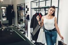 Le flickan som g?r m?nga k?p p? kl?deren, shoppa Kvinna med packeges i h?nder i en bekl?da boutique royaltyfria foton Le flickan som g?r m?nga k?p p? kl?deren, shoppa Kvinna med packeges i h?nder i en bekl?da boutique royaltyfria foton