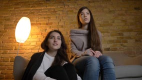 Le fond de plan rapproché vers le haut du portrait de deux jeunes jolies femmes observant un film TV dans un appartement conforta photos stock Le fond de plan rapproché vers le haut du portrait de deux jeunes jolies femmes observant un film TV dans un appartement conforta photos stock