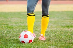 Le footballeur de jeune femme donne un coup de pied la boule sur le terrain de football photographie stock libre de droits Le footballeur de jeune femme donne un coup de pied la boule sur le terrain de football photographie stock libre de droits