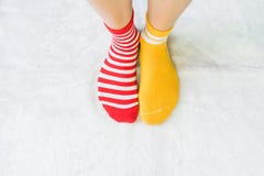 Le gambe in calzini due colori alternano, supporto laterale rosso e giallo sul pavimento bianco del tessuto fotografia stock Le gambe in calzini due colori alternano, supporto laterale rosso e giallo sul pavimento bianco del tessuto fotografia stock