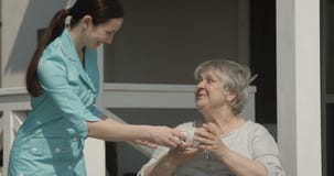 Le gardien de maison de repos donne une tasse de café au retraité heureux souriant ensemble sur le tir de Sunny Day sur la caméra banque de vidéos Le gardien de maison de repos donne une tasse de café au retraité heureux souriant ensemble sur le tir de Sunny Day sur la caméra banque de vidéos