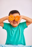 Le garçon d'enfant dans une chemise de turquoise, souriant et tenant deux a coupé l'orange à la hauteur d'oeil - fruit et nourrit photos libres de droits Le garçon d'enfant dans une chemise de turquoise, souriant et tenant deux a coupé l'orange à la hauteur d'oeil - fruit et nourrit photos libres de droits