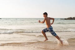 Le garçon de l'adolescence court le long de la plage photographie stock Le garçon de l'adolescence court le long de la plage photographie stock