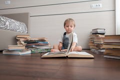 Le garçon est entouré par des livres images stock Le garçon est entouré par des livres images stock