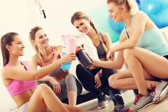 Le giovani donne raggruppano il riposo alla palestra dopo l'allenamento fotografia stock Le giovani donne raggruppano il riposo alla palestra dopo l'allenamento fotografia stock