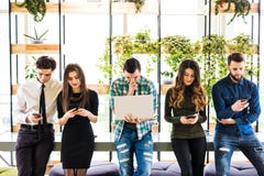 Le groupe d'amis se tenant sur la table et chacun emploient ses divices dans la pièce moderne de bureau Ensemble amusement dans l image stock Le groupe d'amis se tenant sur la table et chacun emploient ses divices dans la pièce moderne de bureau Ensemble amusement dans l image stock