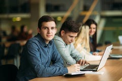 Le groupe d'étudiants universitaires étudiant dans la bibliothèque d'école, une fille et un garçon utilisent un ordinateur portab photographie stock libre de droits Le groupe d'étudiants universitaires étudiant dans la bibliothèque d'école, une fille et un garçon utilisent un ordinateur portab photographie stock libre de droits